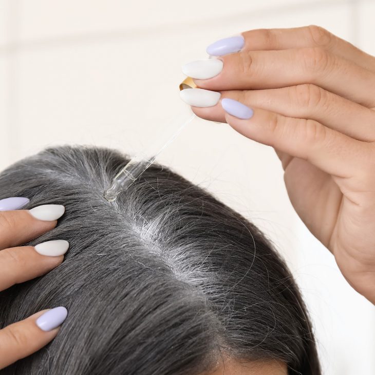 Woman applying serum to her hair