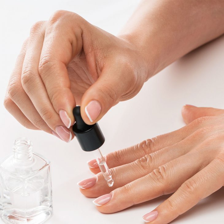 Woman applying vitamin-rich cuticle oil