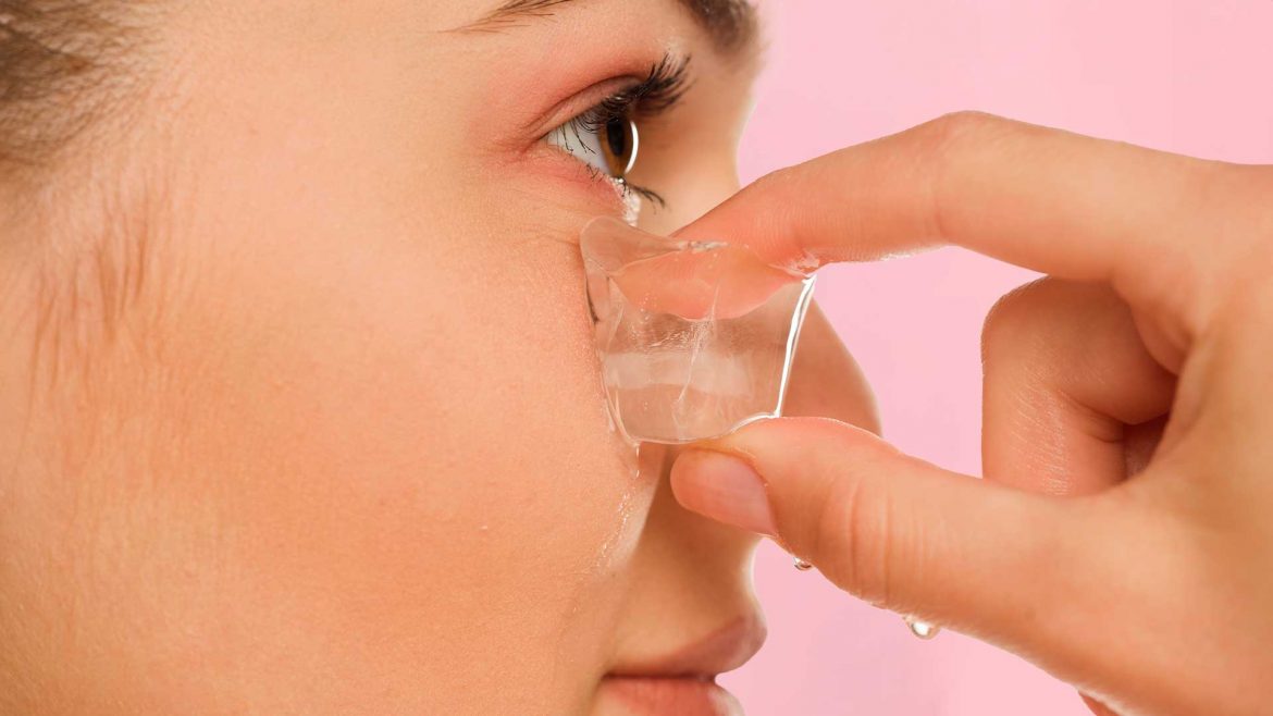 A woman applying ice under her eye