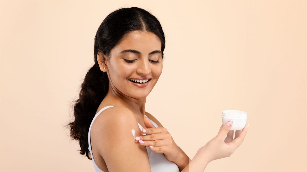 Woman applying body lotion to her skin