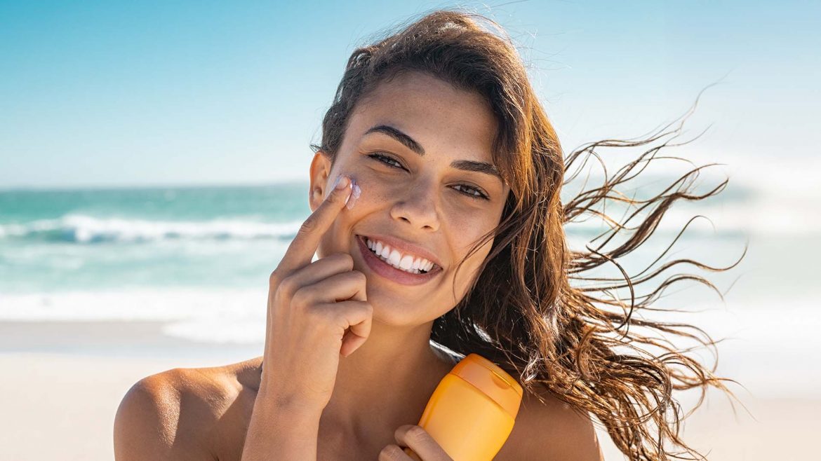 Woman applying sunscreen to her face.