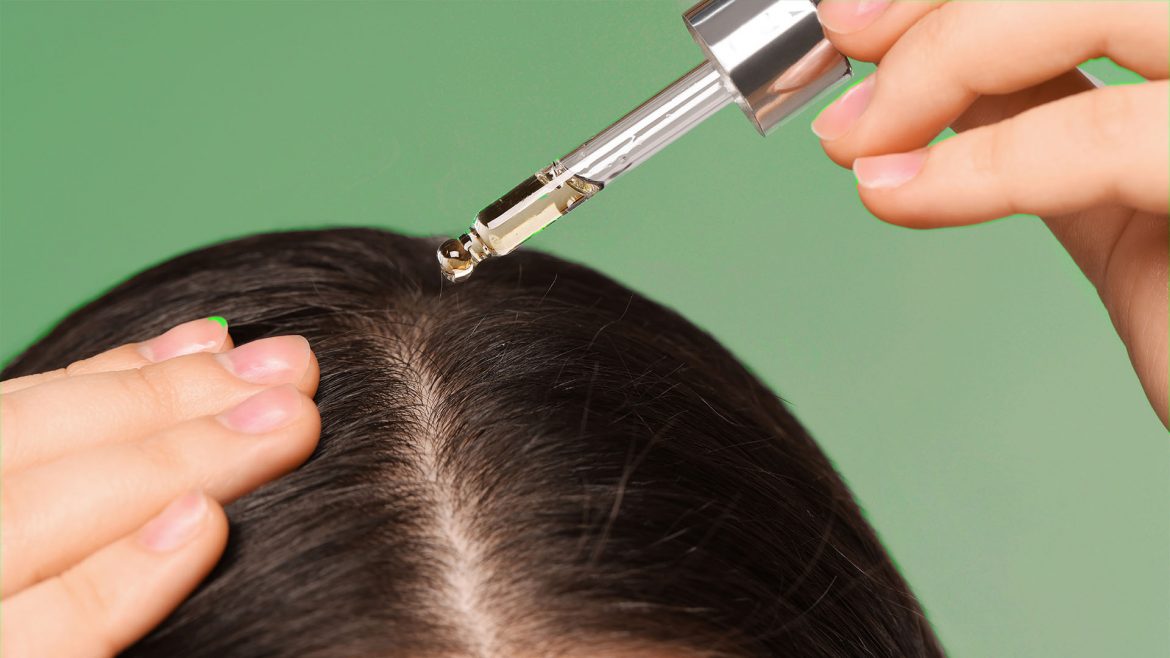 Woman applying bhringraj oil to her scalp