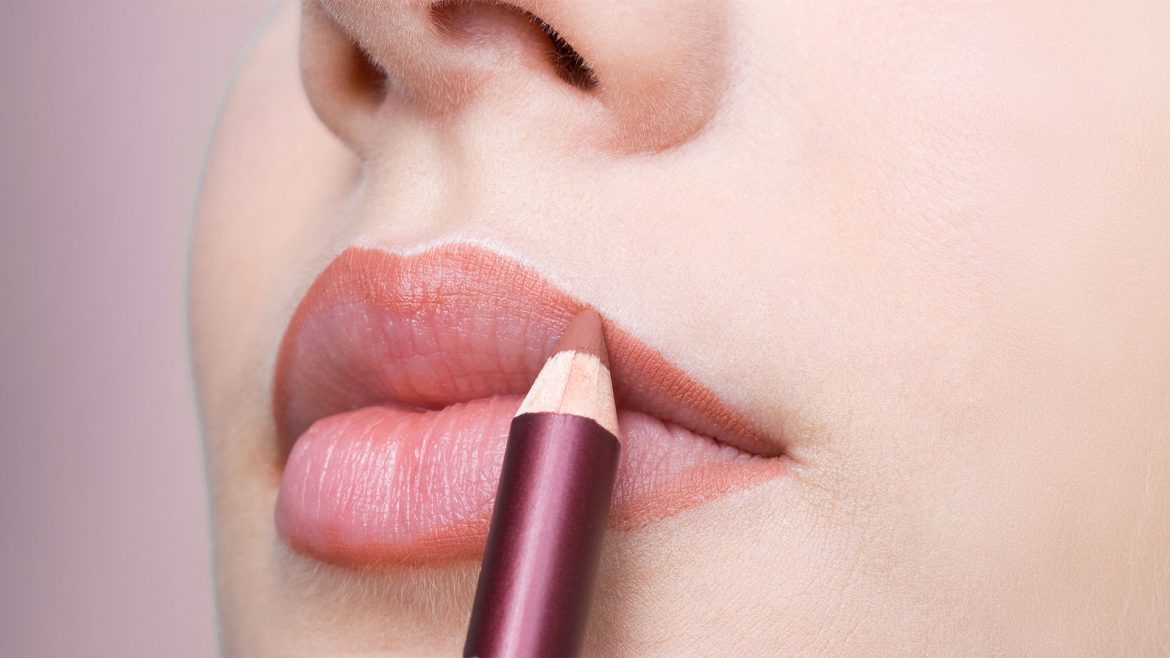 Woman applying nude lipstick