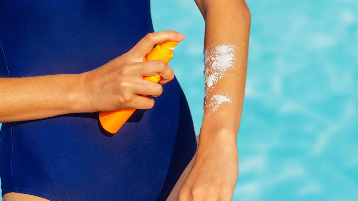 Woman using sunscreen spray