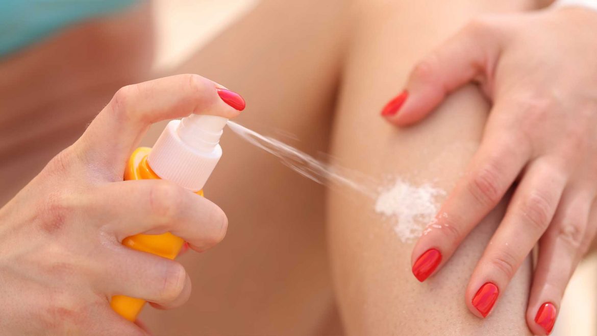 Woman using sunscreen spray