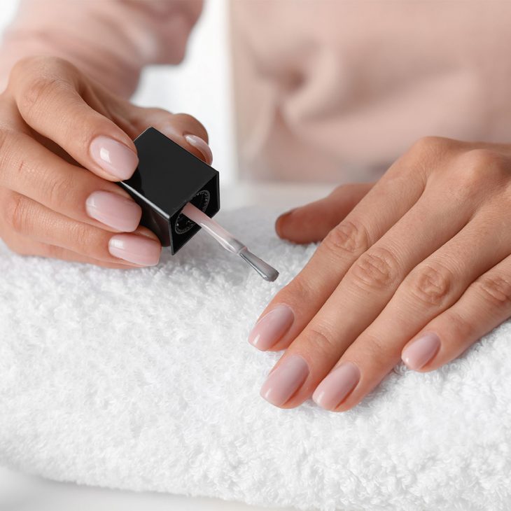 Woman applying base coat for her French manicure