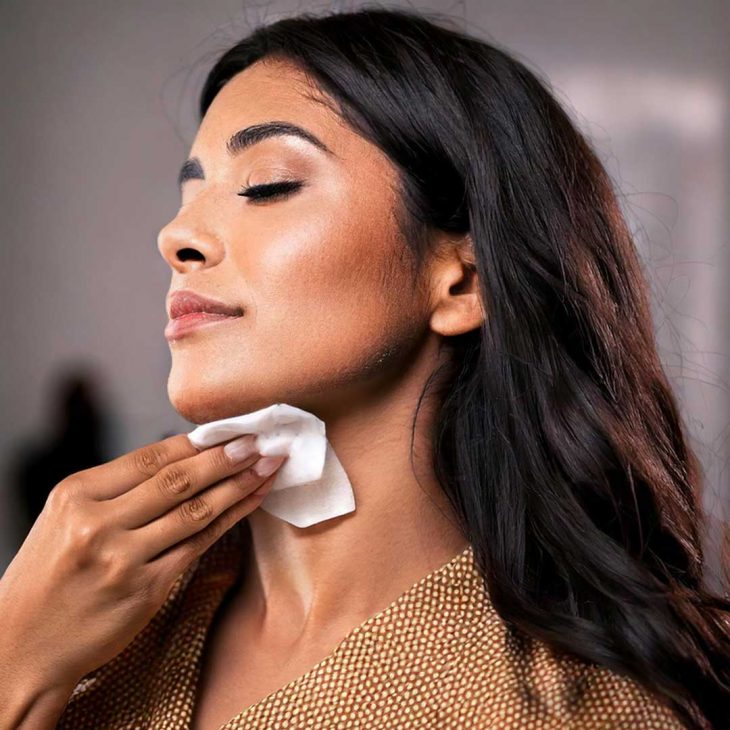 Woman wiping makeup off her neck