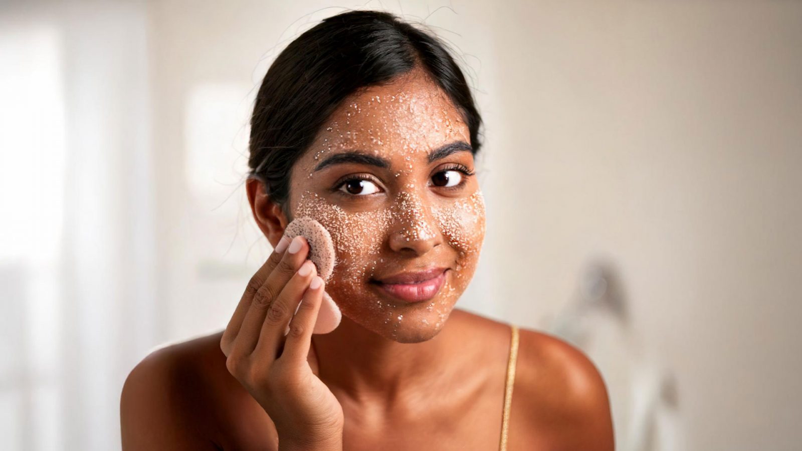 Woman applying scrub on her face